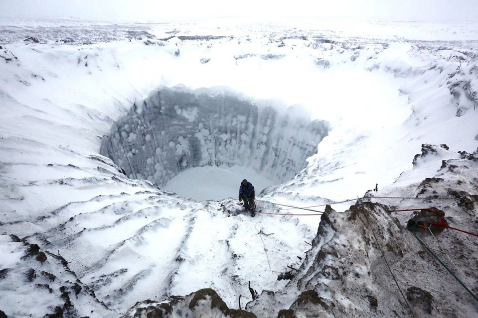 Руски научник стоји на ивици мистериозног кратера недавно откривеног у сјеверној Русији. Једна од теорија његовог настанка јесте да се запалио гас заробљен под земљом. (фото: Vladimir Pushkaryov/Russian Center for Arctic Exploration)